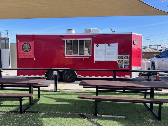 Thai To go red food truck parked with picnic tables out front