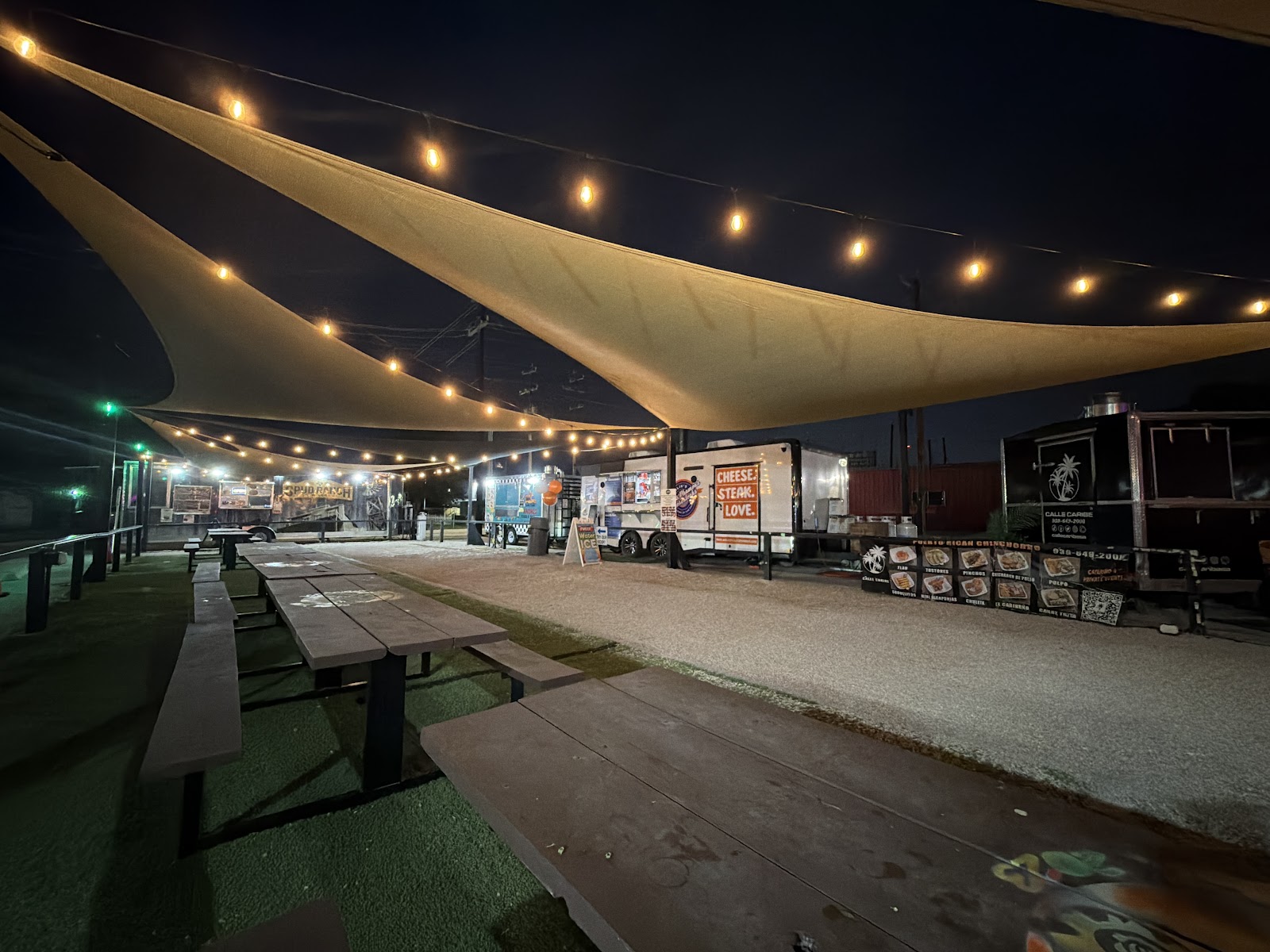 Food truck park at night lit with string lights